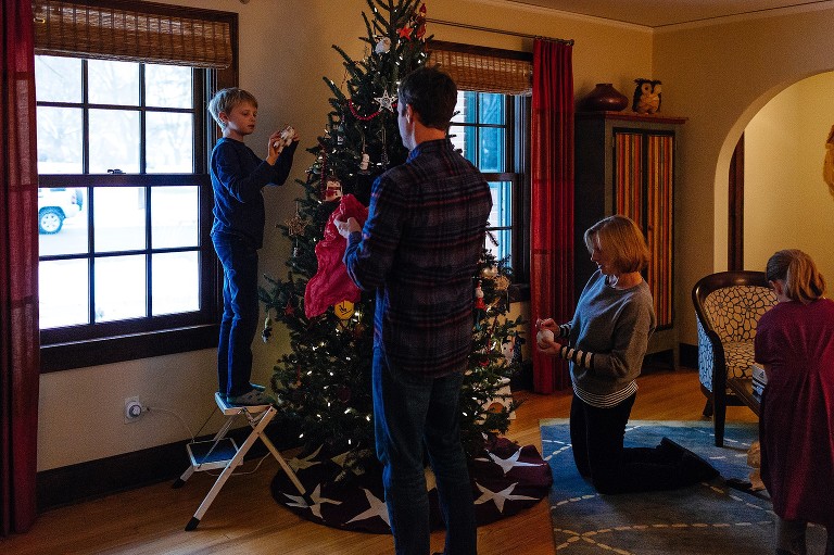 Family decorates Christmas tree in living room