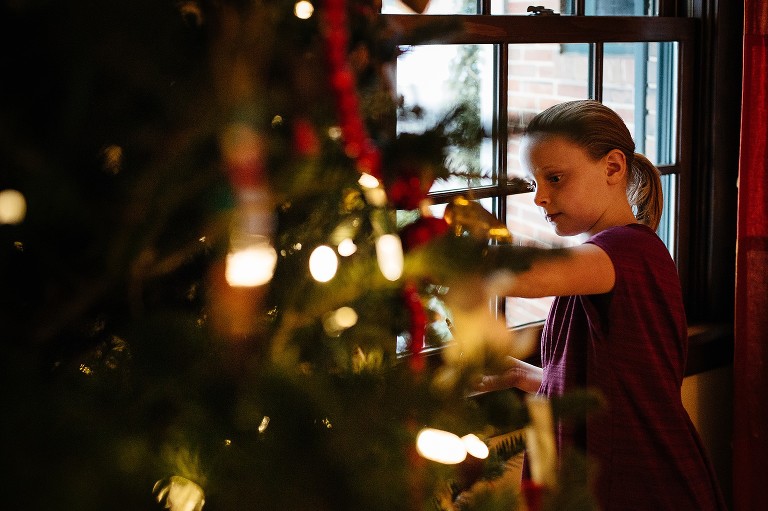 Girl decorates Christmas tree in living room