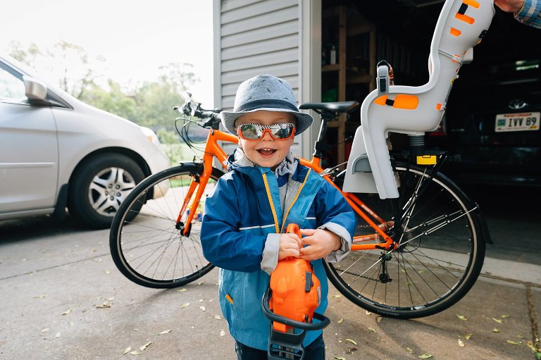 Preschooler holds toy saw in front of bike