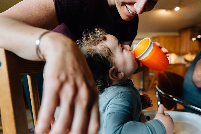 Toddler boy looks as mother while drinking from sippy cup