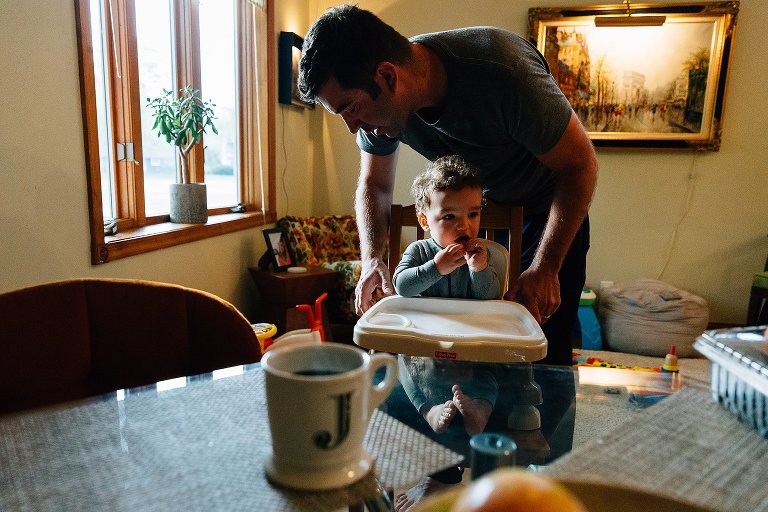 Dad clips toddler into high chair tray