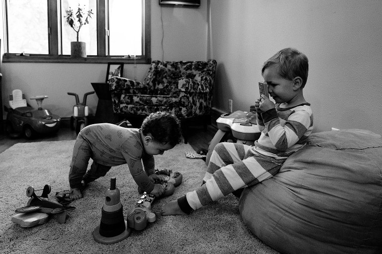 Preschooler pretends to take toddler brother's picture with a toy