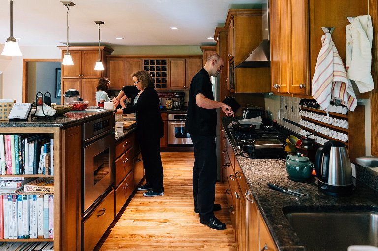 Family works together in the kitchen making waffles and bacon for breakfast 