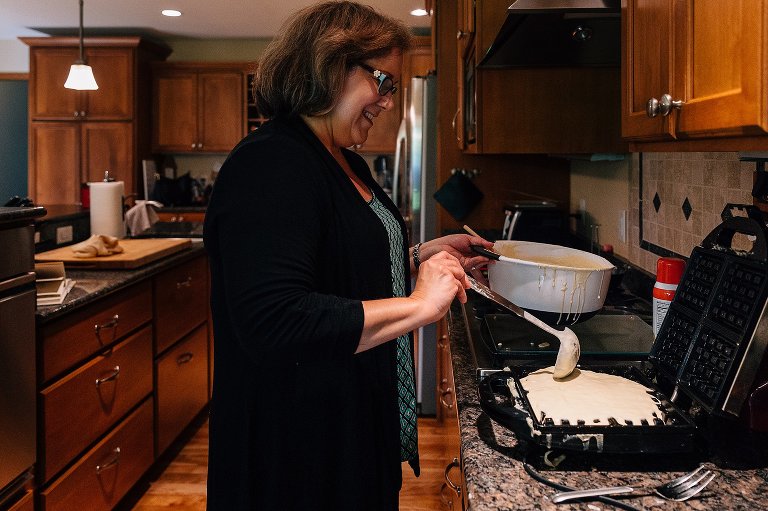 Woman ladles waffle batter onto waffle iron. 