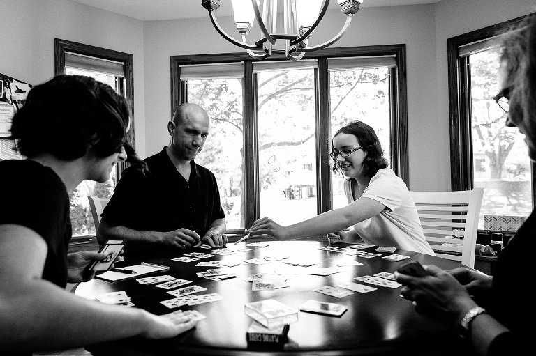 Four people play a card game at a round table. 