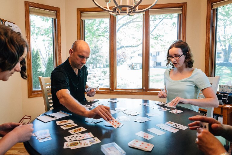Four people play a card game at a round table. 