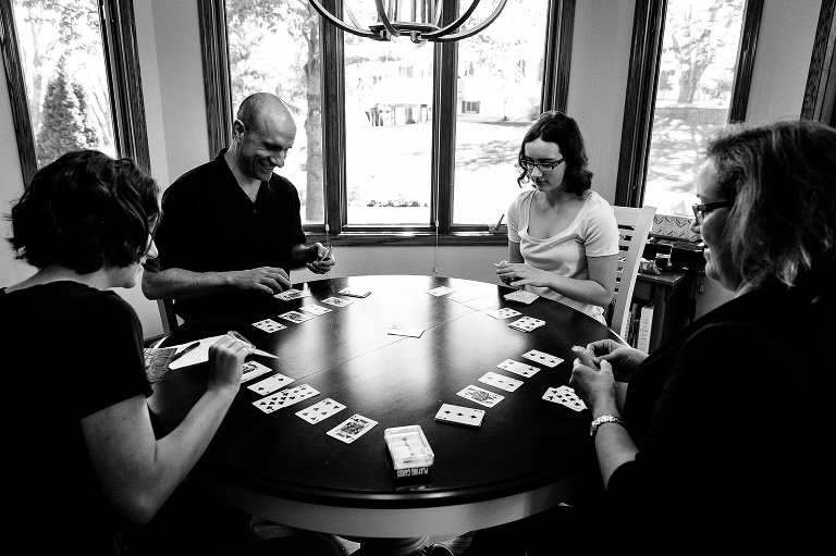 Four people play a card game at a round table. 