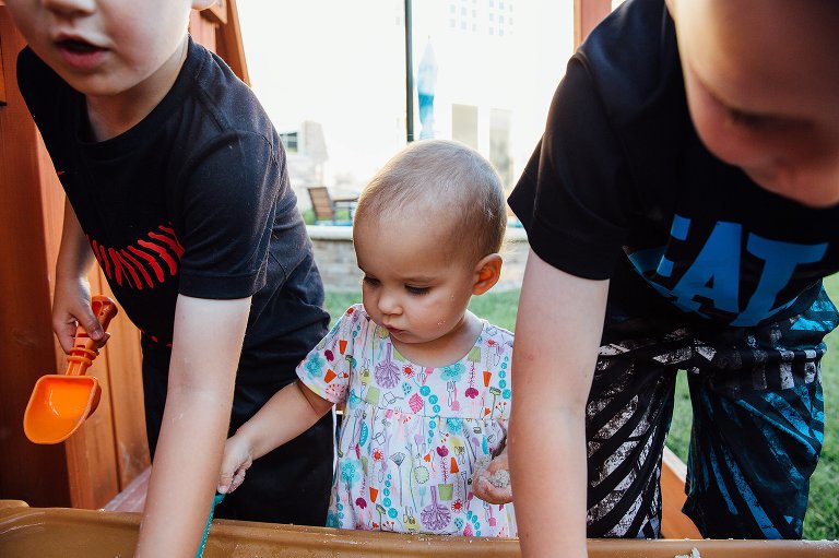 Three siblings play in sand box
