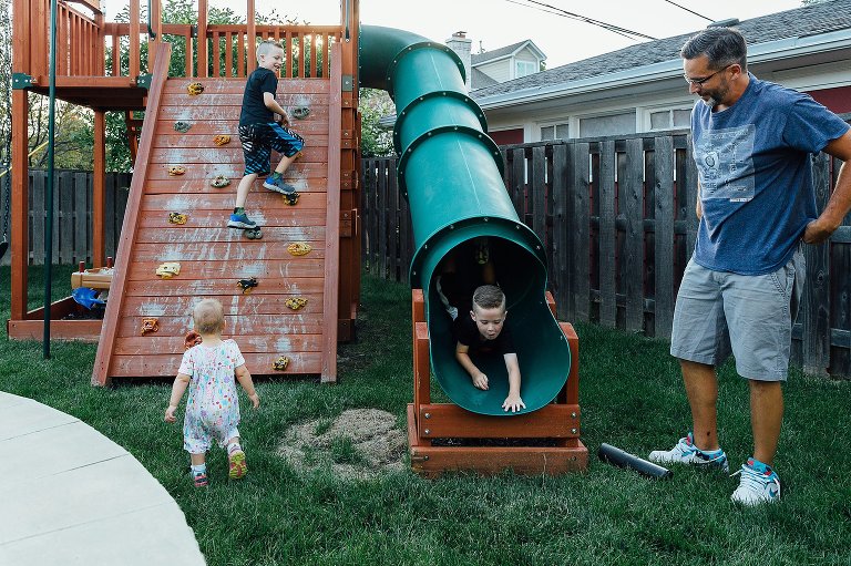 Three kids and Dad on play structure in backyard
