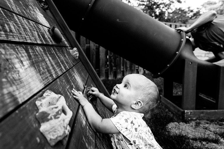 Toddler girl wants to climb climbing wall, while Dad looks for young boy in slide