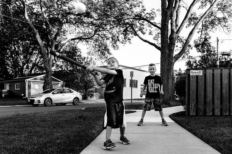 Young boys hits baseball in front yard