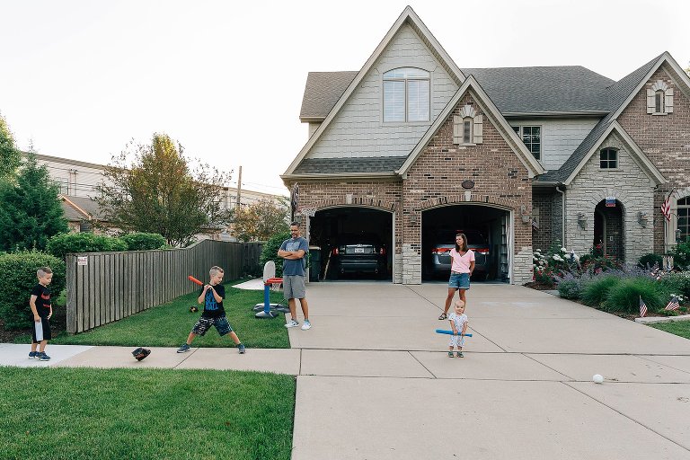 Family plays baseball in front of home 