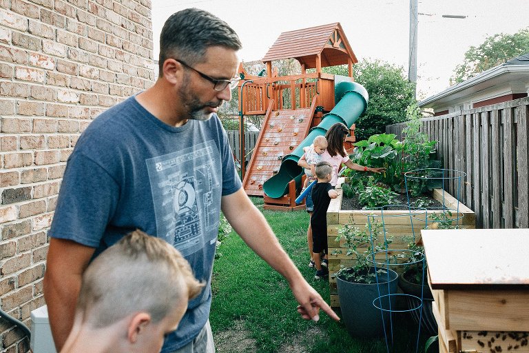 Mom, daughter and younger son look at garden. Dad and older son look at backyard bees. 