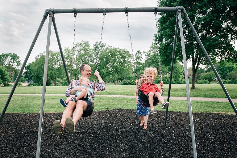 Family plays on swings together at park.