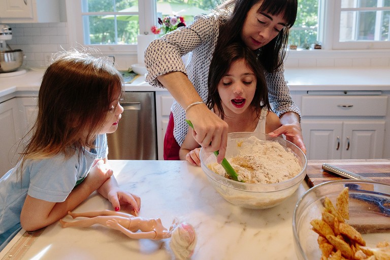 Mom helps daughter stir the heavy apple cake batter 