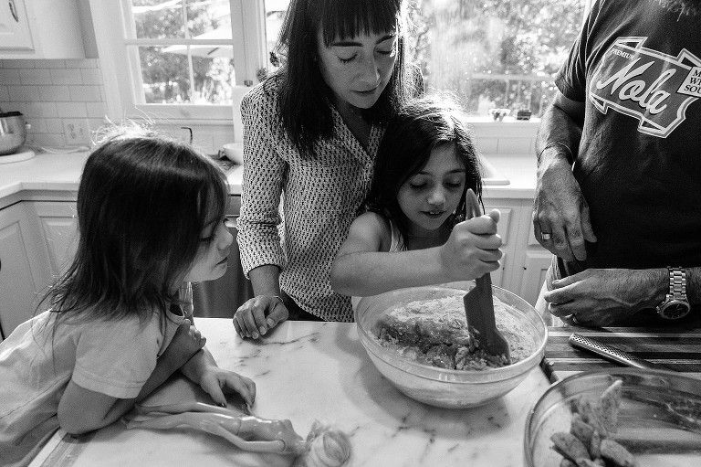 Daughter stirs batter while mom, dad and sister watch and wait their turn 