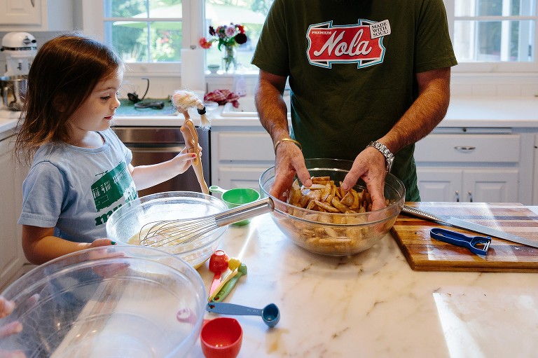 Dad hand tosses the apples and cinnamon mixture 