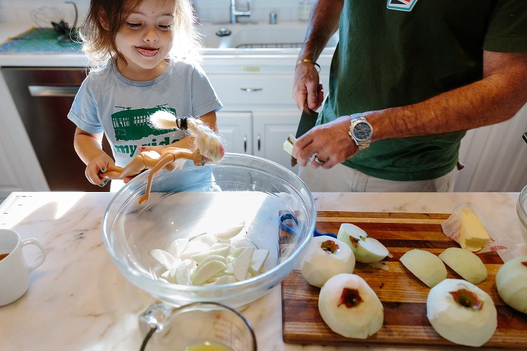 Daughter plays with doll while Dad puts apples in bowl