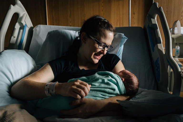 Mother smiles at newborn at hospital 