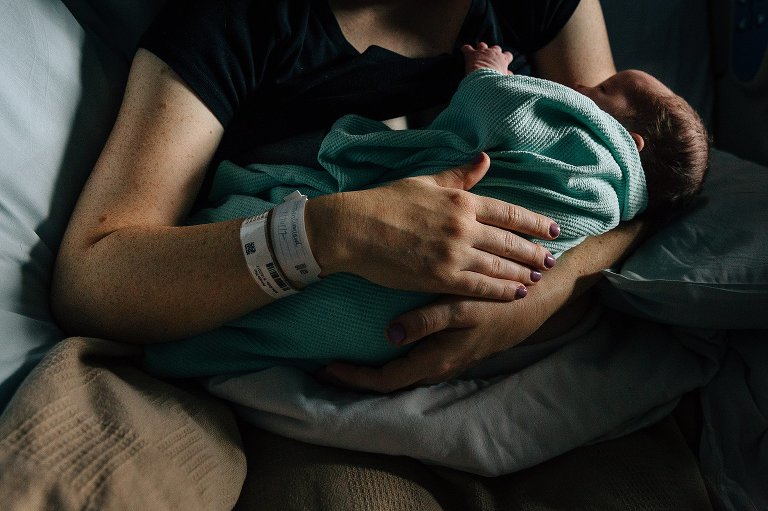 Mother holds newborn in hospital after birth 