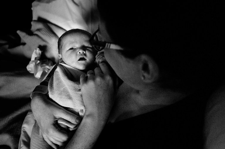 Mom holds baby's finger in morning light 