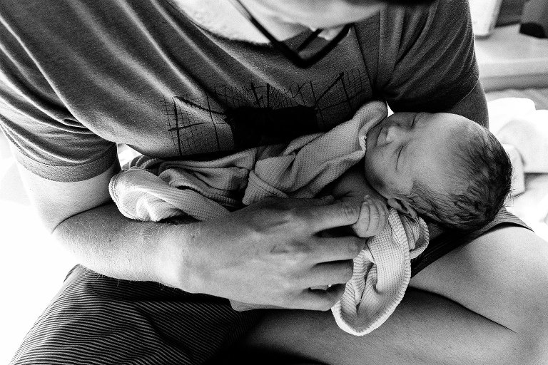 Dad holds newborn's hand in his finger 