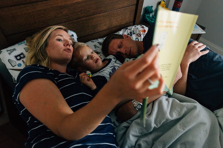 dad falls asleep, mom reads book in bed to preschooler 