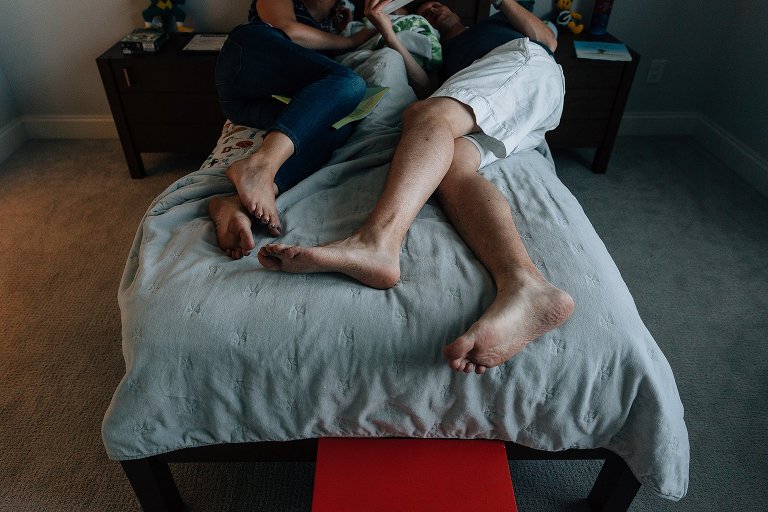 mom and dad read books to preschooler in bed 