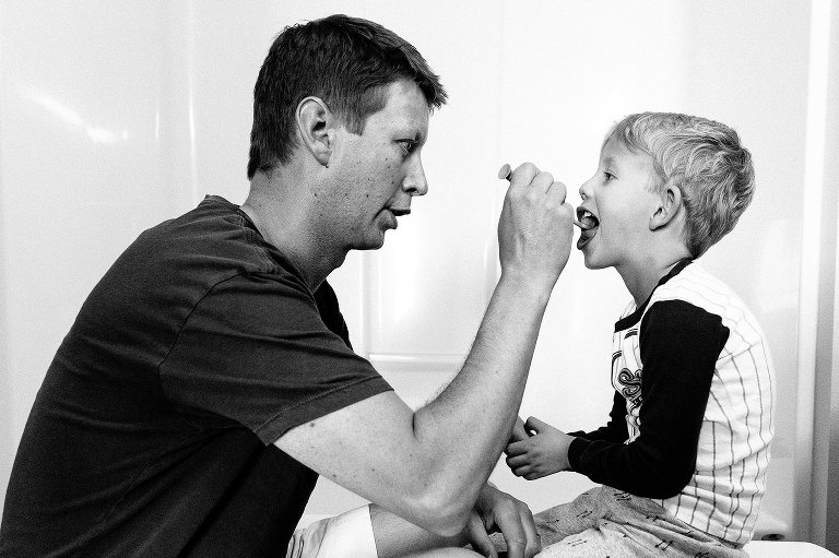 Dad helps brush preschooler's teeth 