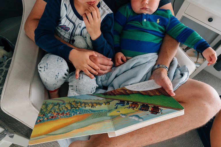 Dad holds books and boys in his lap at storytime 