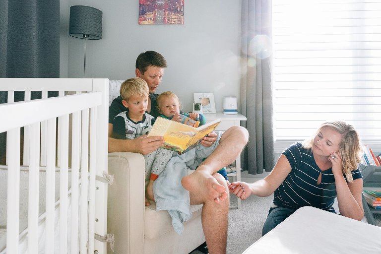 Mom touches toddler's toes while dad reads story 