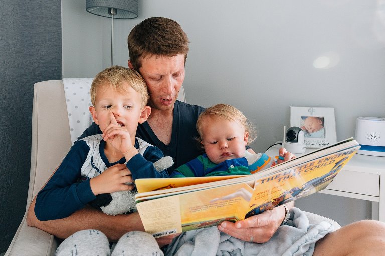 Dad reads book to sons, boy picks nose 