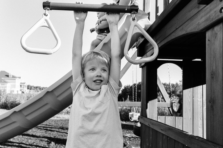 Preschool boy hands on rings, Mom holds toddler going down the slide 