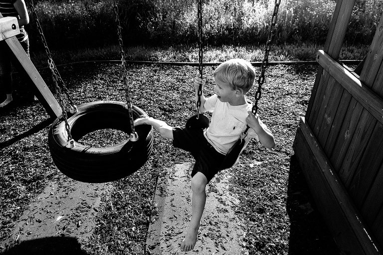 preschool boy sits on the swing