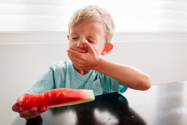 boy wipes away watermelon juice from mouth