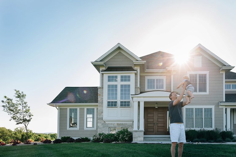 Dad tosses toddler son in air in front of family home in summer 