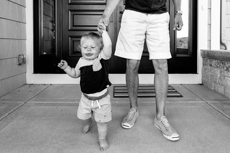 Dad holds toddler's hand to help him walk 