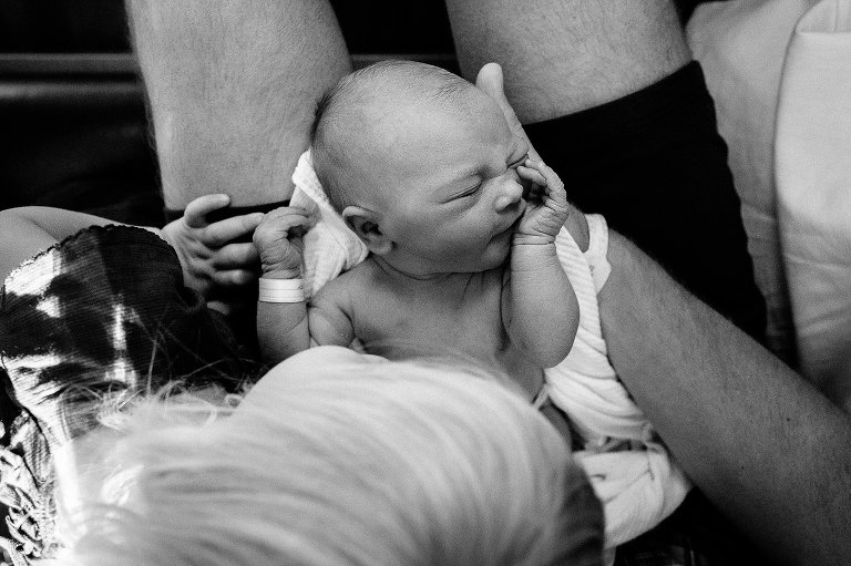 Dad holds newborn while toddler looks on