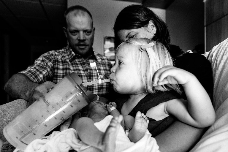 Big sister gets drink from mom's water