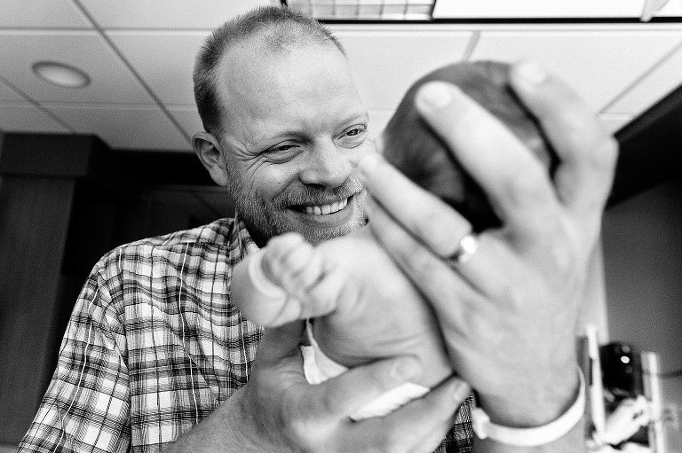 Dad holds newborn daughter, smiling