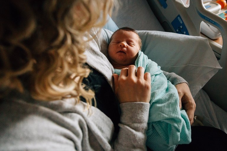 Mom holds newborn girl at hospital after being born. 