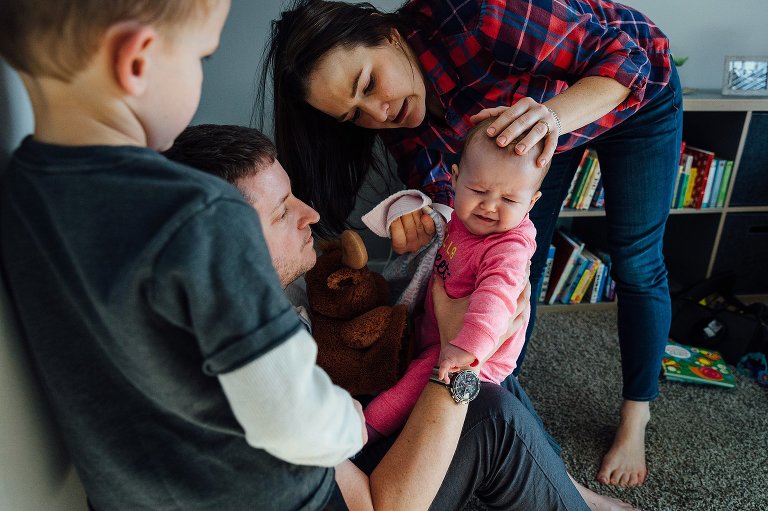 mother wipes baby's nose with tissues. She grimaces. 