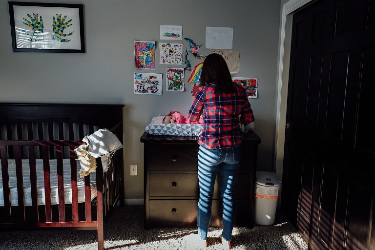 mom changes baby in nursery 