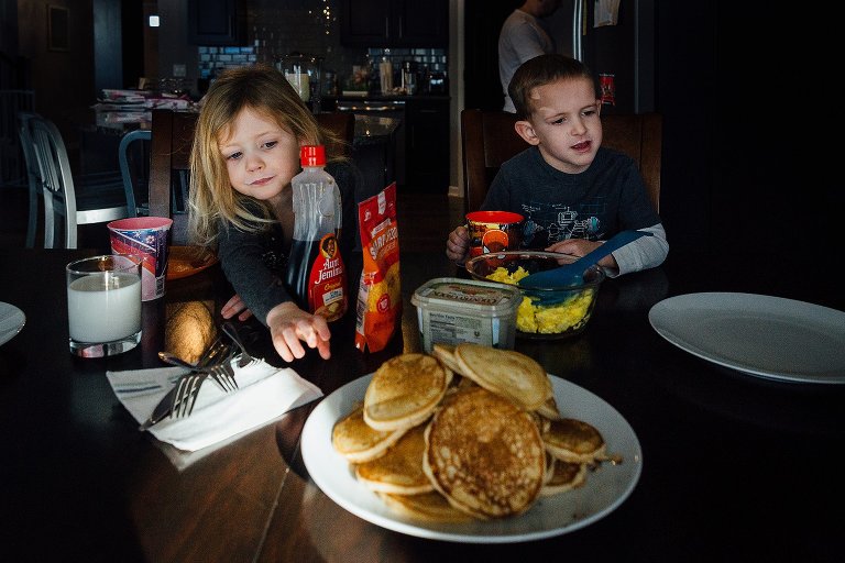 Young girl reaches for a mound of hot pancakes 