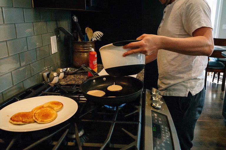 Dad pours pancake batter into skillet. 