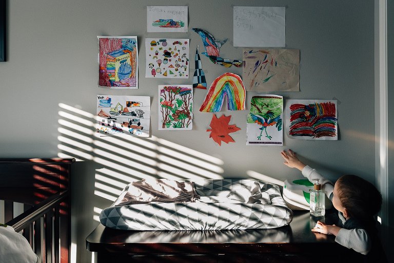 Young boys points to art wall above baby's changing table