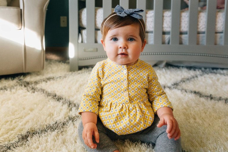 Color portrait of 9 month old baby sitting in nursery.