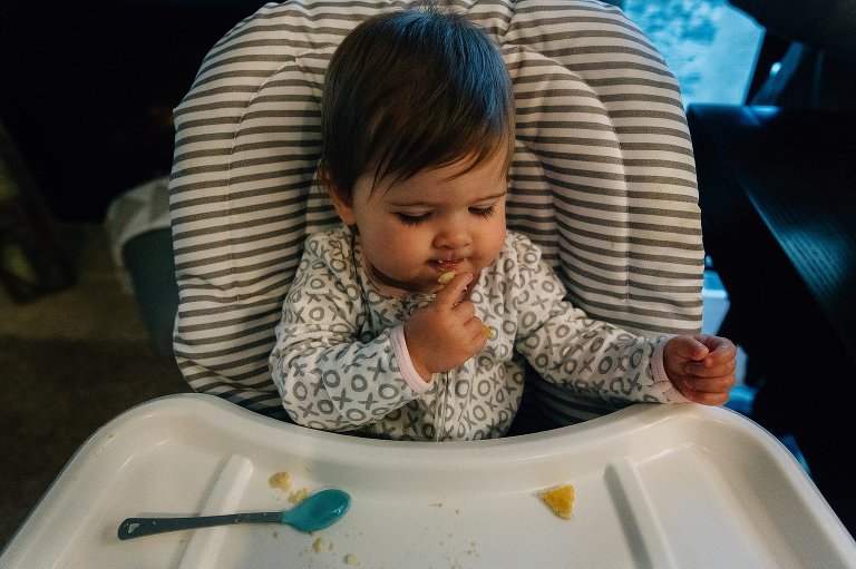 Baby feeds herself in high chair