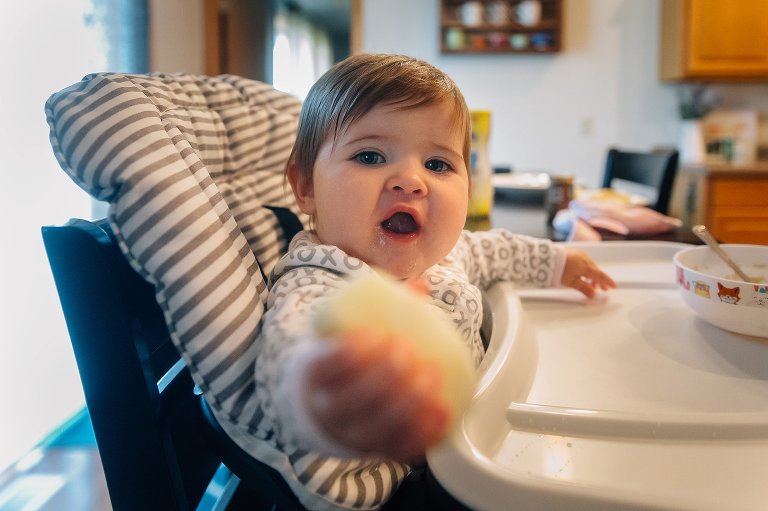 Baby shares pear slice with camera.