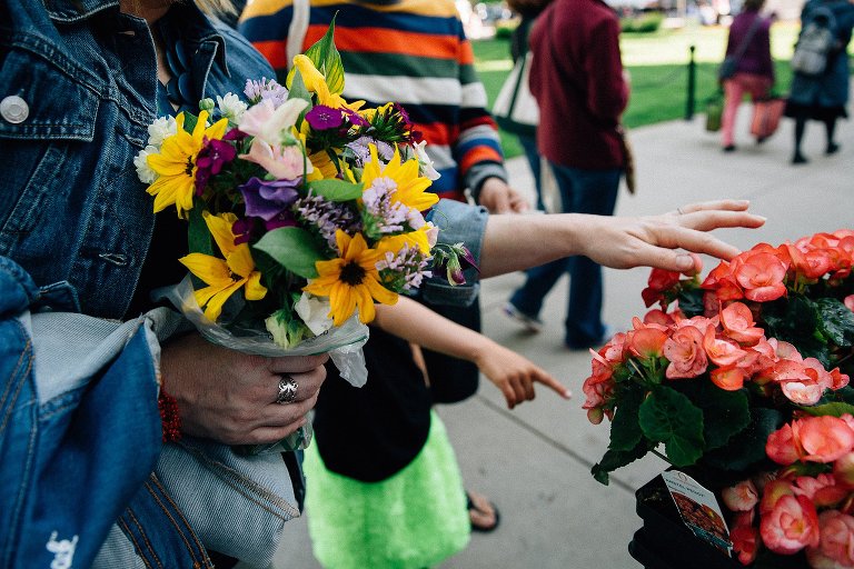 Girl points to bouquets of summer flower at farmers market 